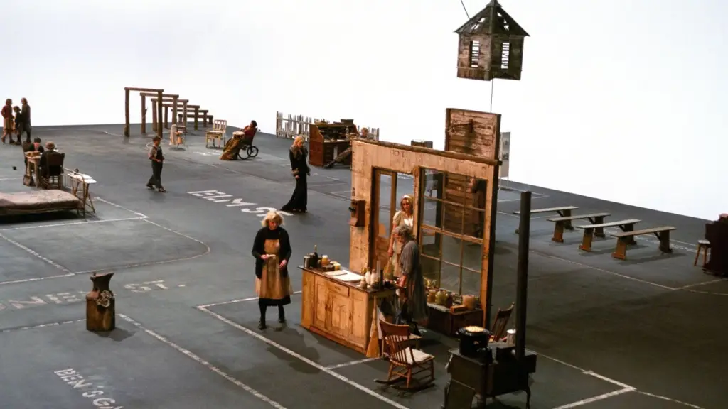 A still from Dogville depicting its minimalist stage design and central characters